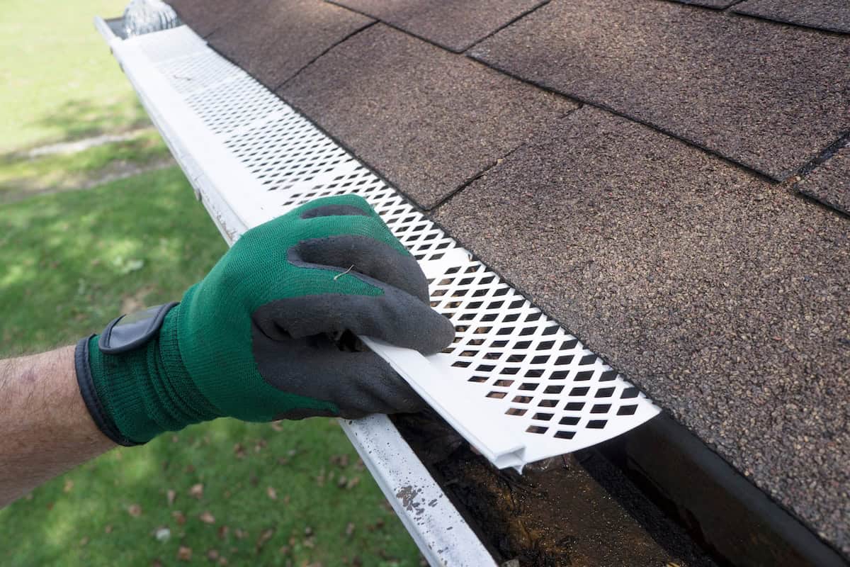Contractor adjusting plastic gutter guards to get them to fit.