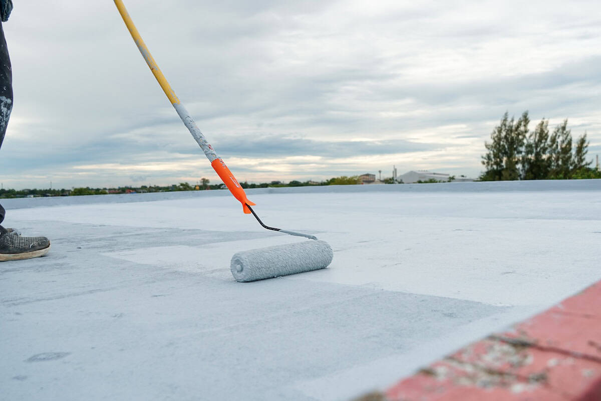 White roof waterproof sealant being applied with roller brush