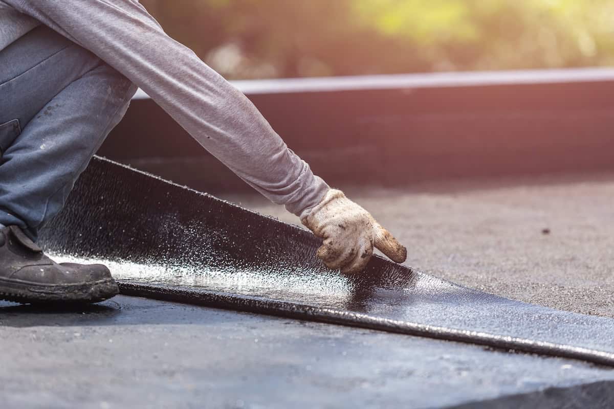 worker installing waterproofing system on roof