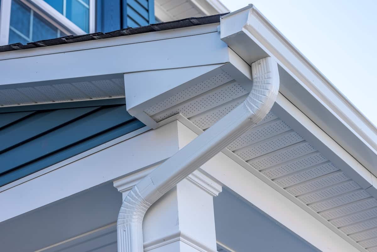 Newly installed white metal gutters on blue house