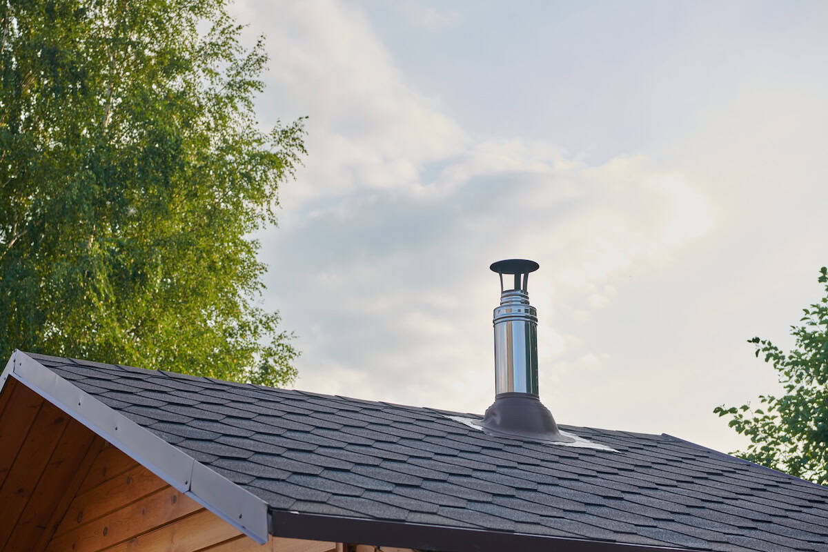 Stainless steel metal chimney pipe on the roof of the house