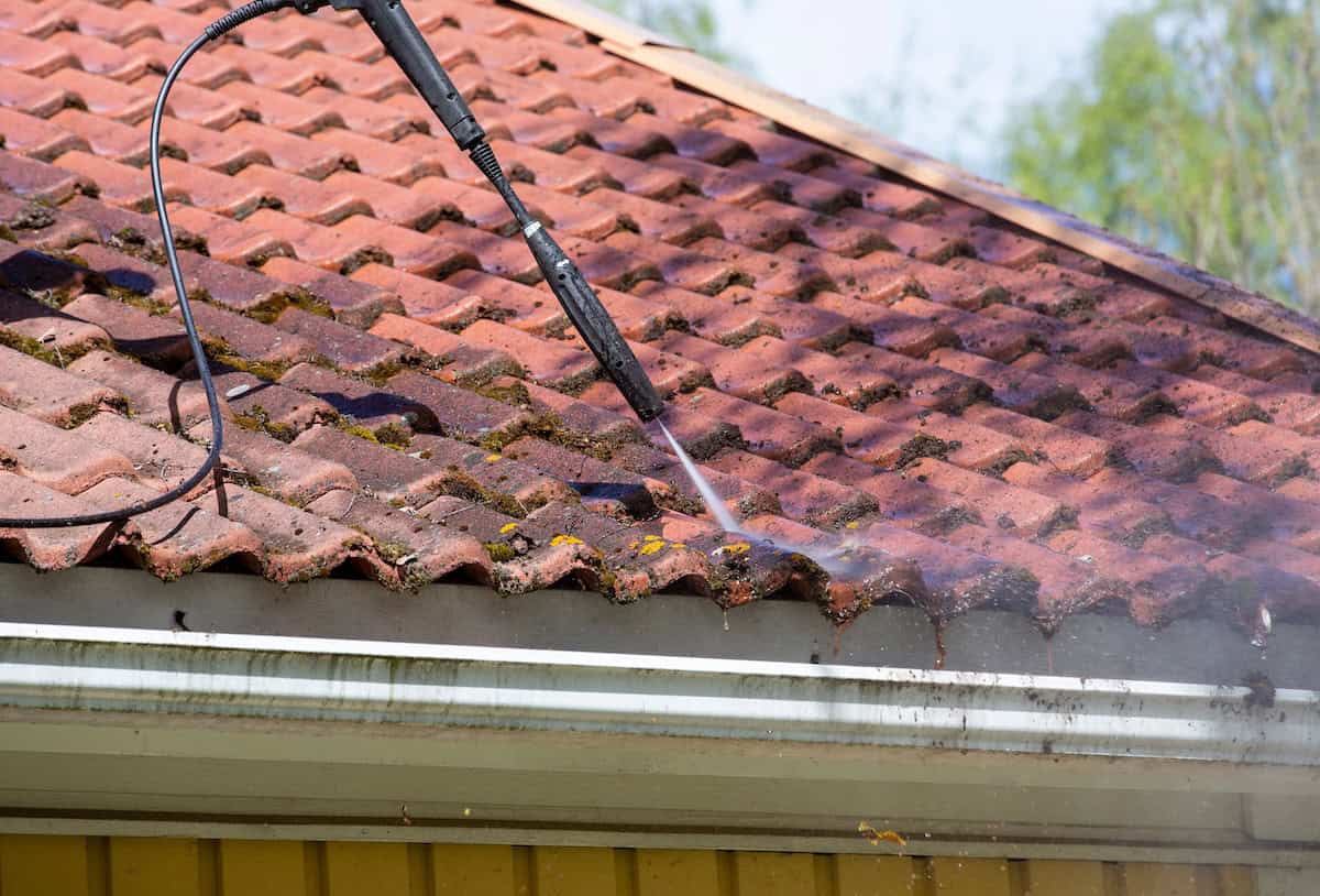 washing the moss from the roof with a high pressure washer
