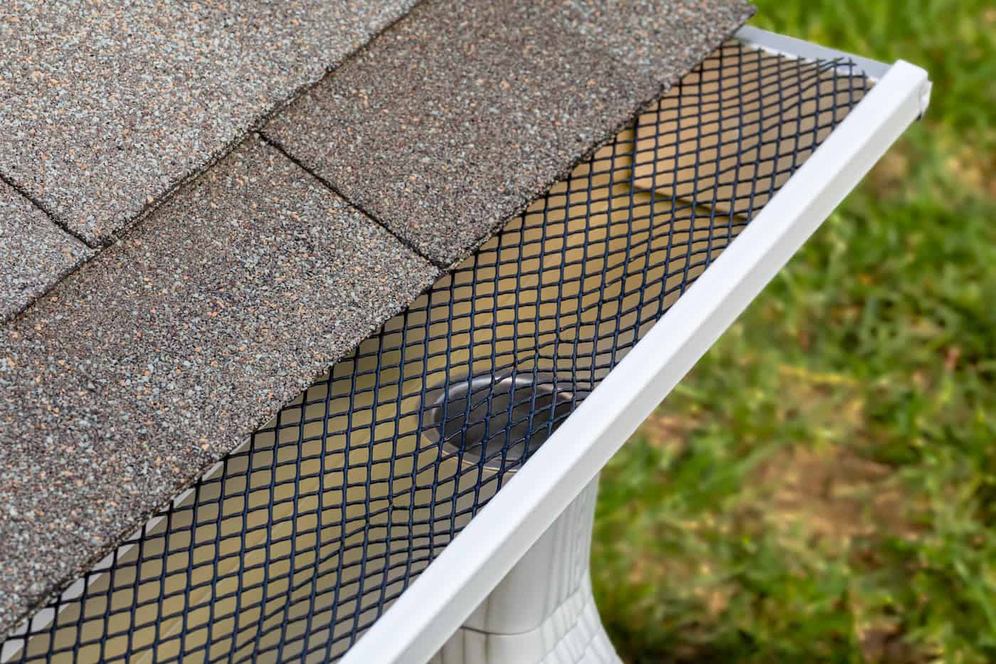 Installing gutter guard mesh screen on rain guttering. Home maintenance, yardwork and roof damage concept