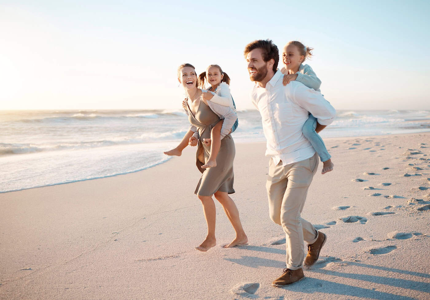Happy, family and piggyback with children at beach for outdoor adventure, vacation and weekend trip. Sunset, father and mother with kids by ocean in summer for fun holiday, love and travel in Florida.