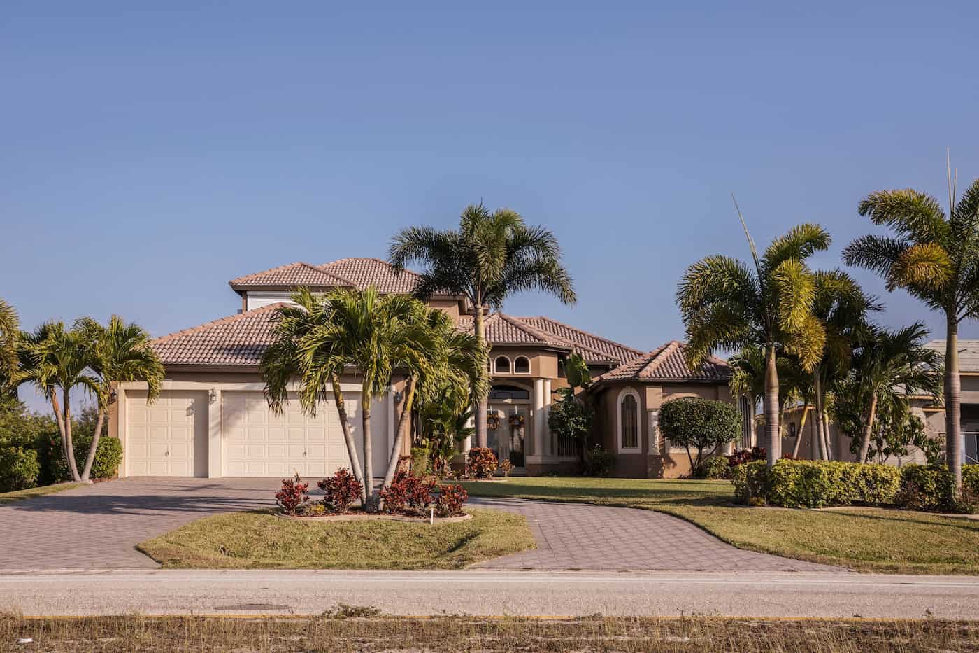 Typical Southwest Florida concrete block and stucco home in the countryside with palm trees, tropical plants and flowers, grass lawn and pine trees. Florida. South Florida single family house