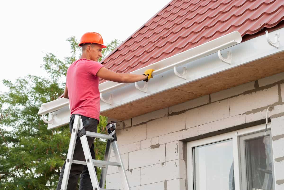 worker installs the gutter system on the roof